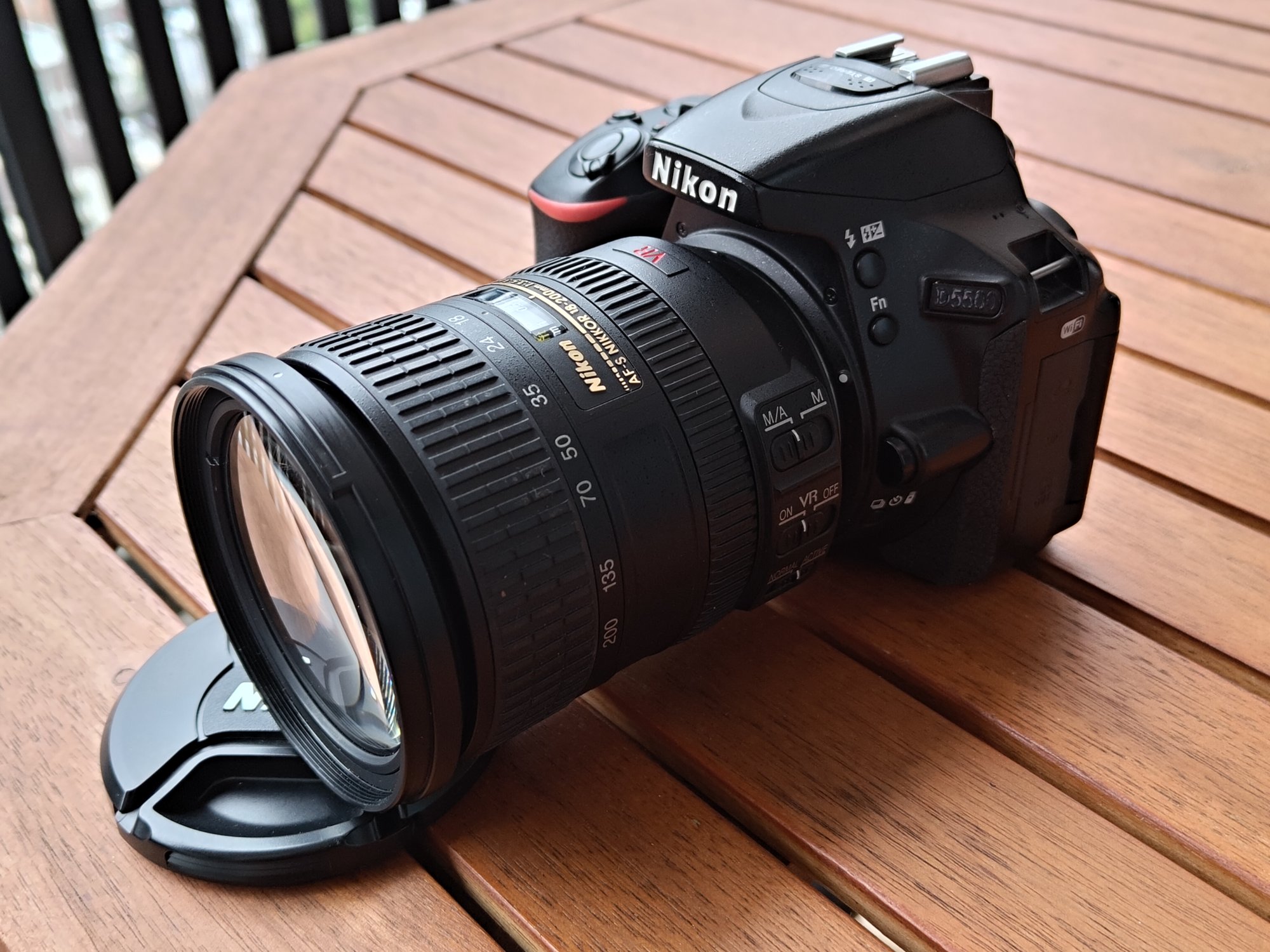 Nikon D5500にAF-S DX 18-200mm F3.5-5.6G VRを付けた状態。木のテーブルの上に置いている