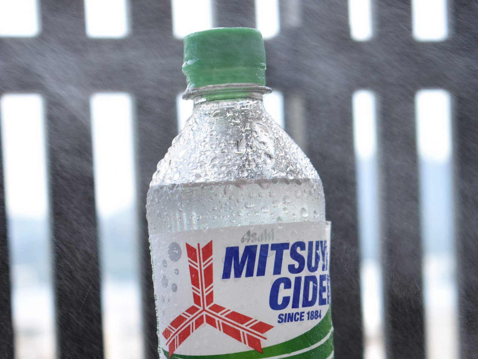 露出補正+1の三ツ矢サイダー。ボトルの両側の柵の前に白い霧が写る
