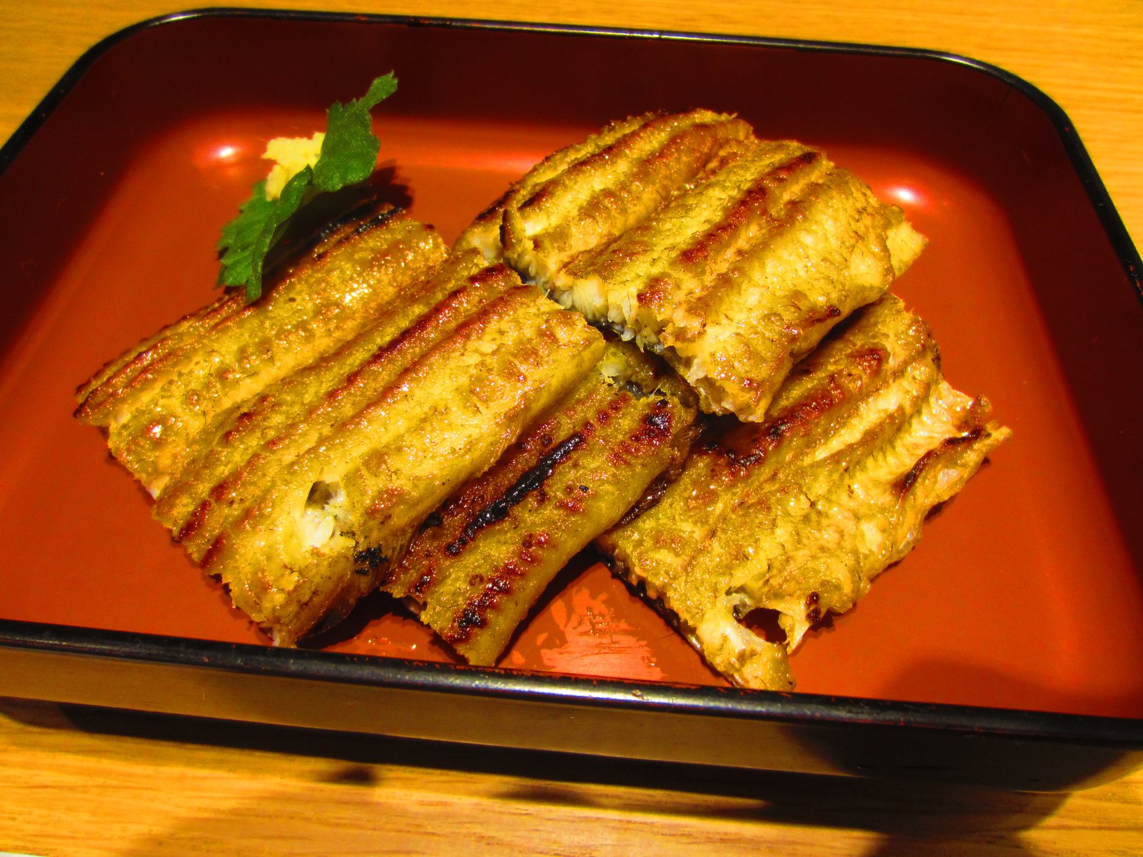 赤い器に並んだ、焼き目の筋が入った鰻の白焼き
