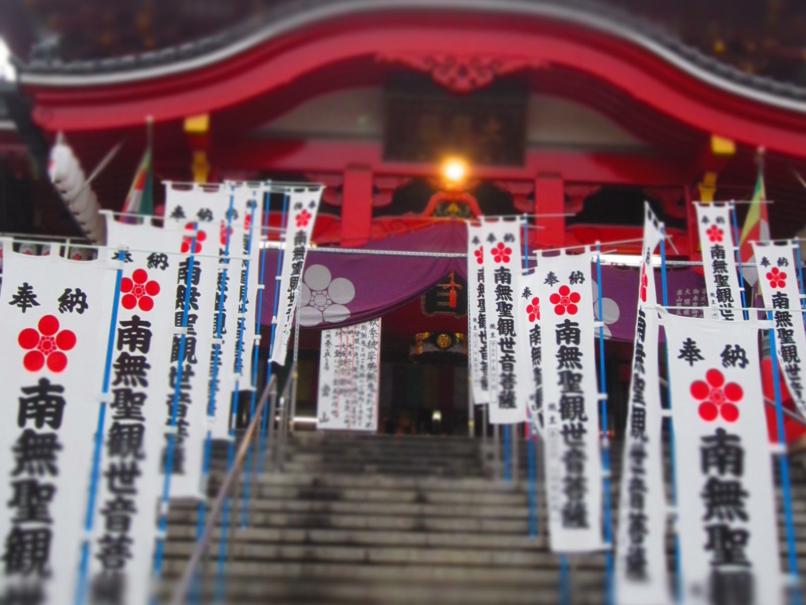 大須観音の境内で、幟が並んだ石段。ジオラマ風で幟の文字のあたりだけくっきりし、奥の建物の屋根と手前の石段がぼけている