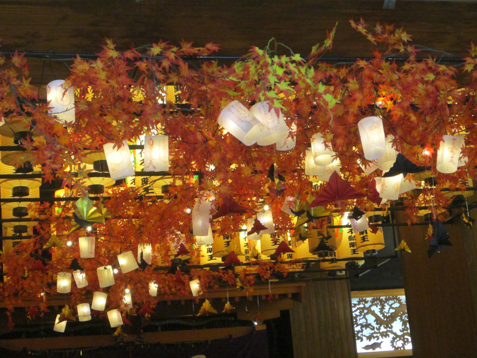 天井から下がる紅葉の飾りと、白や黄色の提灯がびっしり並んでいる様子
