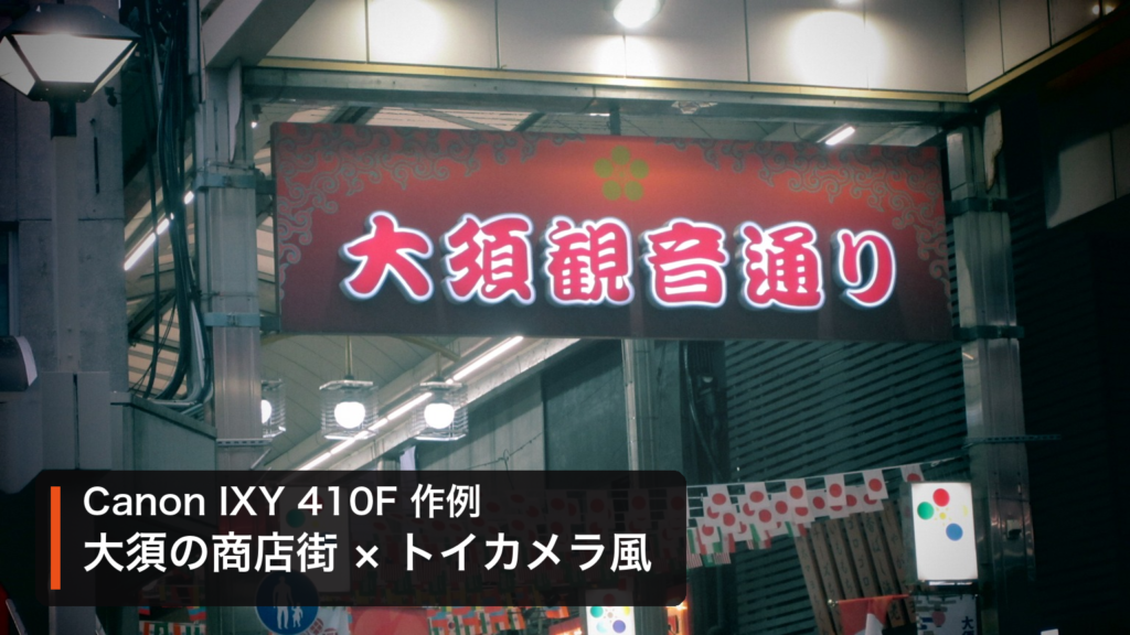 Canon IXY 410Fのトイカメラ風モードで撮影した大須観音通りの赤い看板と万国旗。「Canon IXY 410F 作例／大須の商店街 × トイカメラ風」の文字入り