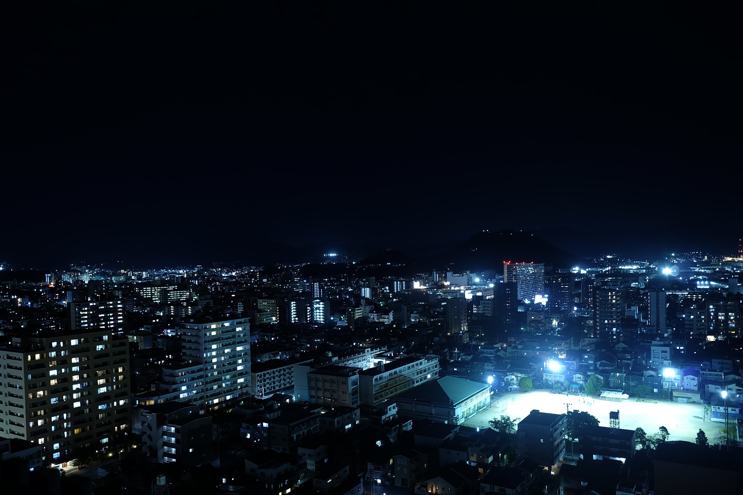 F2.8・1.5秒で撮った夜景。空は黒く、街は青く、グラウンドの光は広がっていない