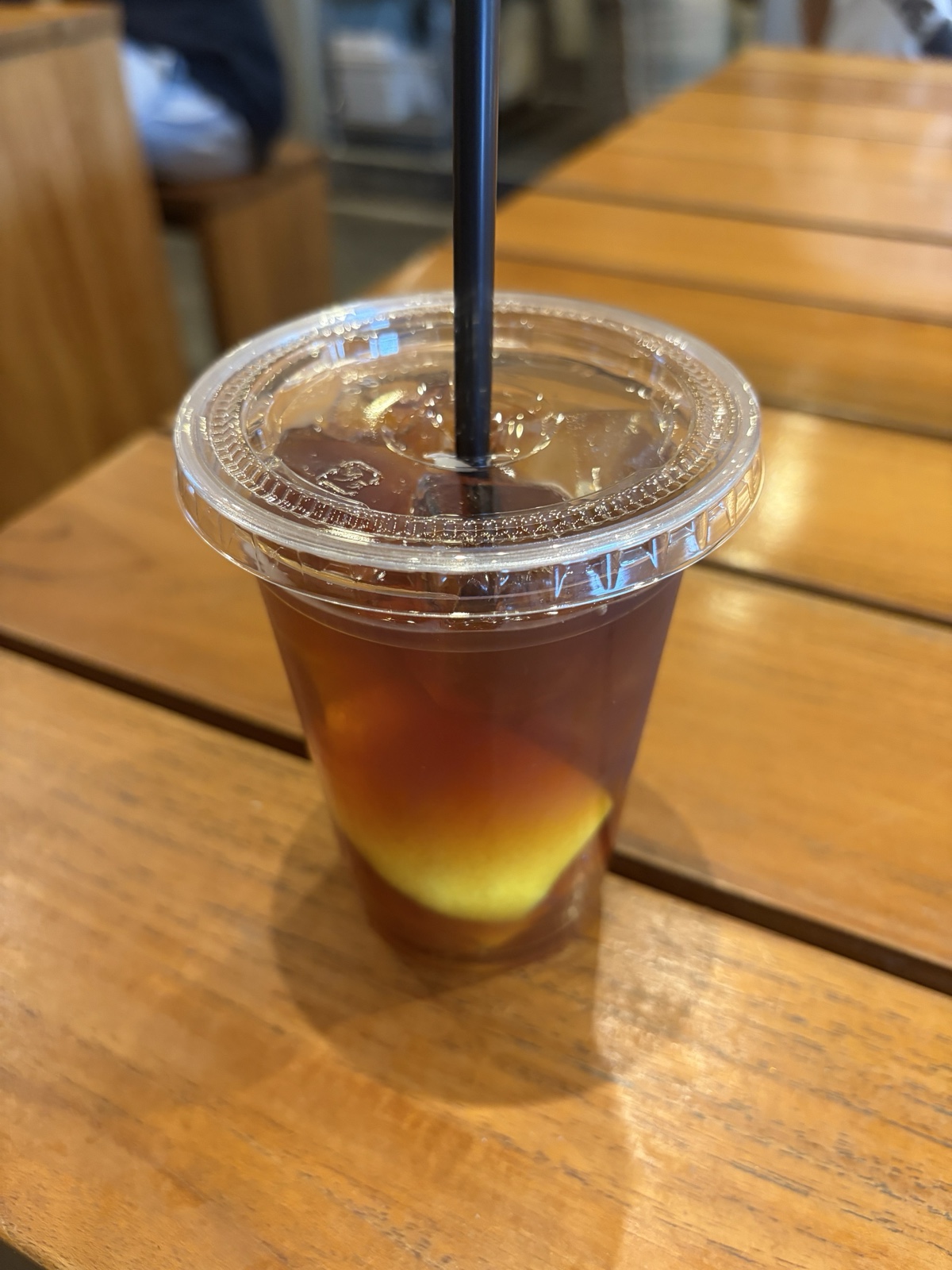 木のテーブルに置いたレモンコーヒー。透明なカップの底にレモンが入っている