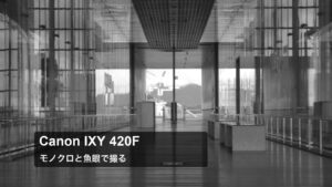 ガラス張りの通路を奥へ向けて撮ったモノクロの作例。Canon IXY 420F、モノクロと魚眼で撮るの文字入り